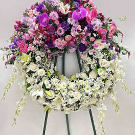 Large floral wreath on an easel with pink, purple, and white flowers
