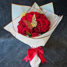 Bouquet of red roses wrapped in white paper with a red ribbon