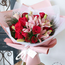 Bouquet of red roses and pink lilies wrapped in pale pink paper