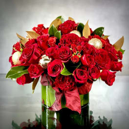 Red rose bouquet in a green glass vase with gold ornaments and ribbon