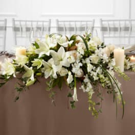 White floral centerpiece with candles on a banquet table