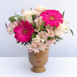 Pink and white flowers arranged in a face-shaped vase