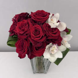 Red roses and white orchids in a clear glass vase