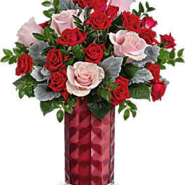 Red and pink roses in a tall red glass vase