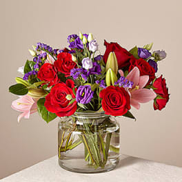 Bouquet of red roses and pink lilies in a clear glass vase