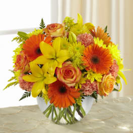 Bright bouquet of orange and yellow flowers in a clear glass vase