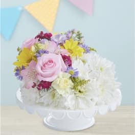 Pastel mixed flower arrangement in a white pedestal bowl