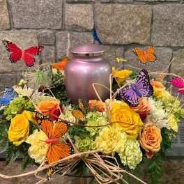 Butterfly-decorated floral arrangement around a pink urn