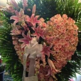 Heart-shaped floral tribute with pink lilies and roses