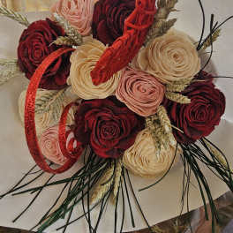 Bouquet of red, blush, and cream roses with wheat and red ribbon accents