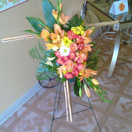 Tall floral standing arrangement with orange, pink, and yellow blooms on an easel