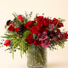 Red roses and pink orchids in a clear ribbed glass vase