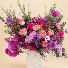 Pink and purple mixed flower arrangement in a white vase