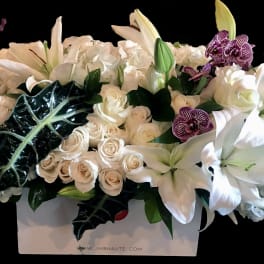 White lilies, roses, hydrangeas, and purple orchids in a white box