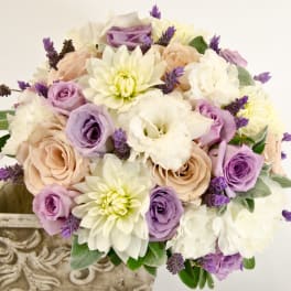 Bouquet of lavender, cream, and blush flowers in a decorative stone planter