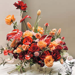 Red and orange floral arrangement with roses and anthuriums in a vase