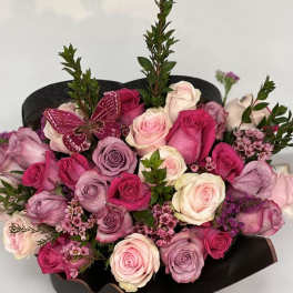Bouquet of pink and lavender roses with a butterfly decoration in black wrap