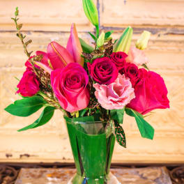 Pink roses and lilies arranged in a clear glass vase