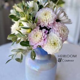 Pink and white flowers arranged in a glass vase with greenery