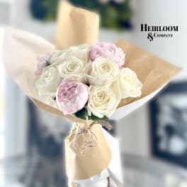 Bouquet of white and pale pink roses wrapped in brown paper