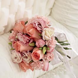 Pink and peach bouquet with roses and carnations tied with white ribbon