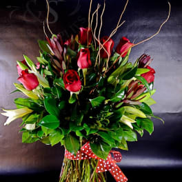 Red roses arranged in a clear glass vase with a polka-dot ribbon