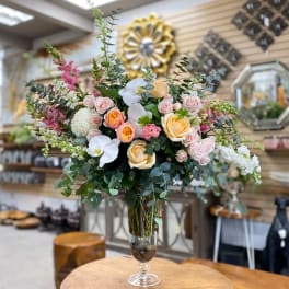 Large bouquet of pastel roses and orchids in a glass vase
