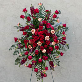 Large standing spray of red roses and mixed flowers on an easel