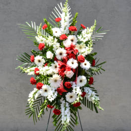 Standing floral spray with white daisies and red carnations on an easel