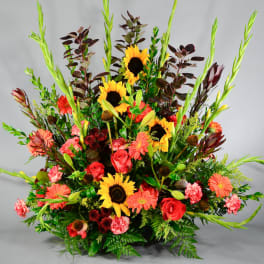 Large mixed bouquet with sunflowers, roses, gerbera daisies, and tall green spikes