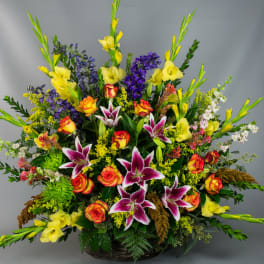 Large mixed bouquet with yellow gladiolus, roses, and purple lilies in a basket