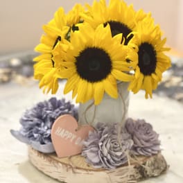 Sunflowers in a birch bark container with lavender flowers and a heart tag