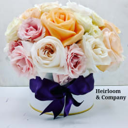 Bouquet of pastel roses in a white hat box with a purple ribbon