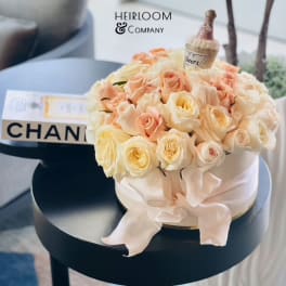 Round bouquet of pale peach and cream roses with a small champagne bottle topper