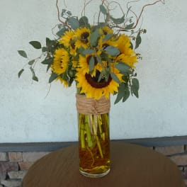 Sunflower arrangement in a tall glass vase with curly branches