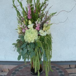 Tall floral arrangement with pink and white blooms in a black vase