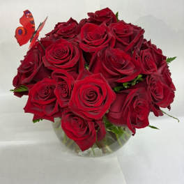 Bouquet of red roses in a clear glass vase with a butterfly pick