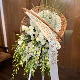 White floral standing spray with a wicker heart and ribbon