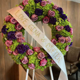 Heart-shaped floral wreath with pink roses, purple blooms, and a ribbon