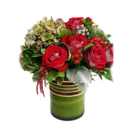 Red roses and mixed greenery in a green glass vase