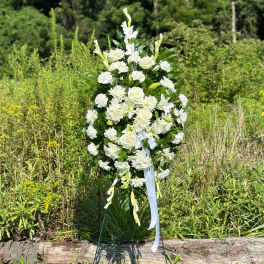 White floral standing spray on a metal easel outdoors