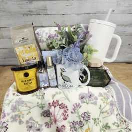 Gift basket with a floral blanket, mug, candle, honey, and lavender items