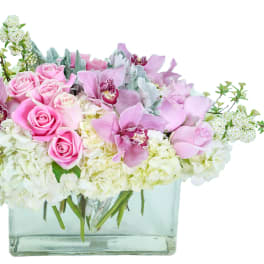Pink roses and orchids in a clear rectangular vase