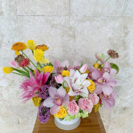 Mixed bouquet of pink, yellow, and white flowers in a round white box