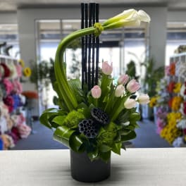 Modern floral arrangement with pink tulips and a white calla lily in a black vase