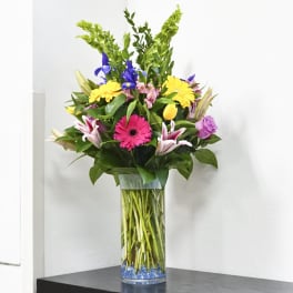Tall mixed bouquet in a clear glass vase with bright flowers