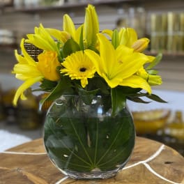 Yellow lilies and a gerbera daisy in a glass vase