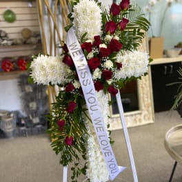 Standing floral cross with red roses and white chrysanthemums, with a memorial ribbon.