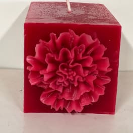 Red square candle with a large flower decoration on the front