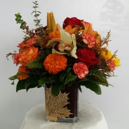 Mixed bouquet in a square glass vase with red, orange, and yellow flowers